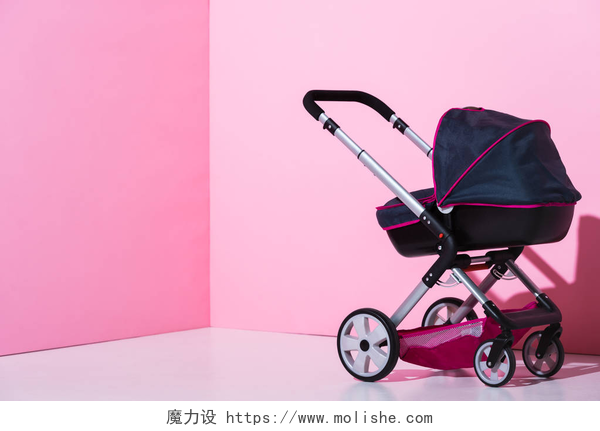 粉红色背景前的婴儿车粉红色和白色的婴儿车，带复制空间